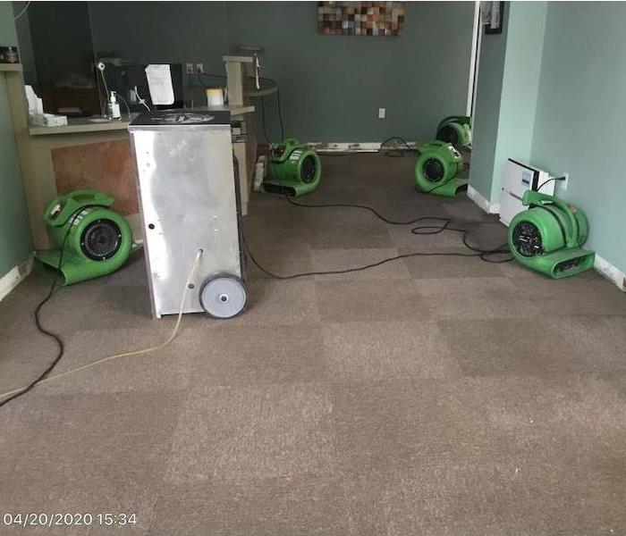 SERVPRO air movers in a room with a missing baseboard